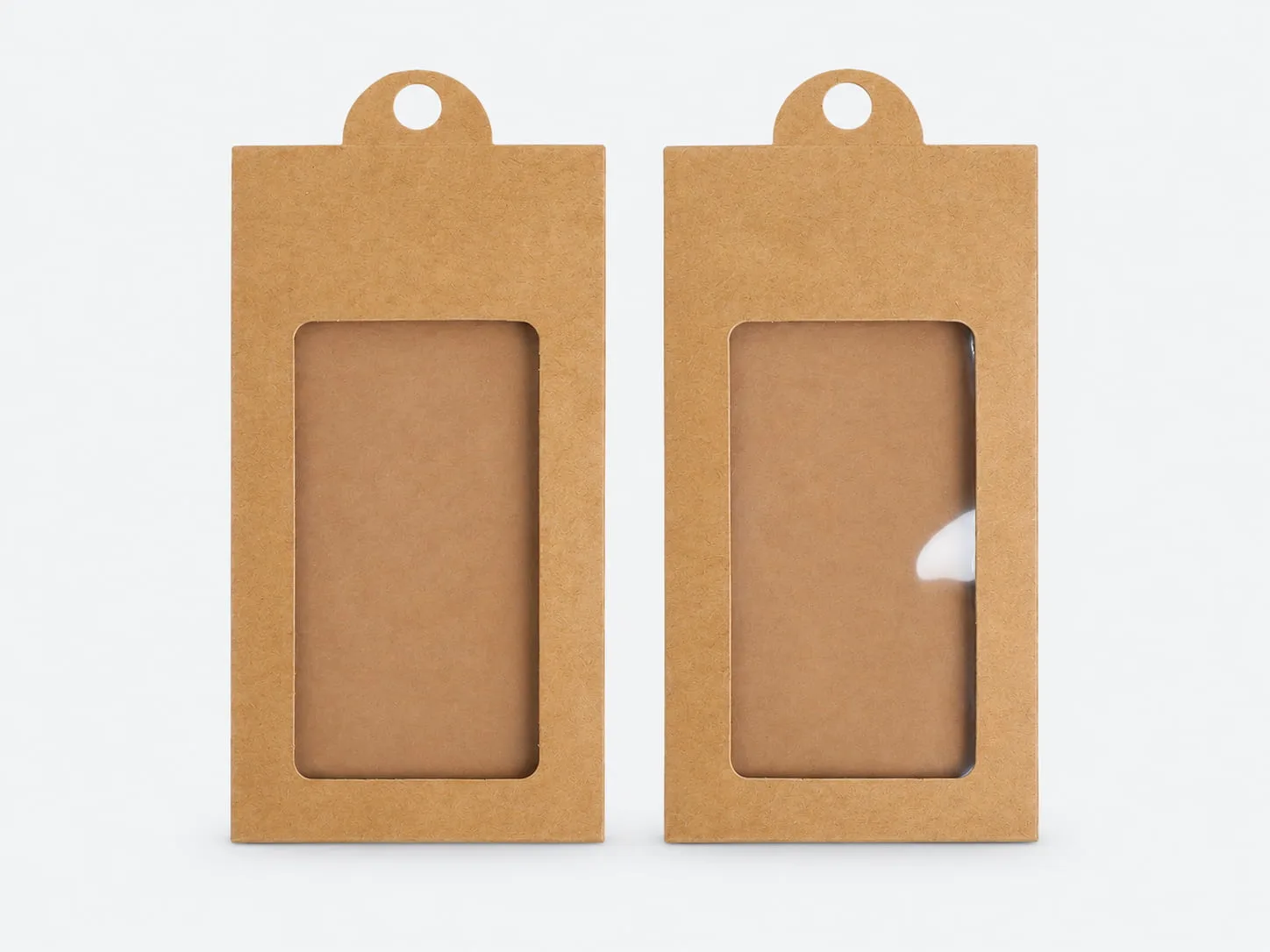 Kraft paper packaging boxes with clear display windows and hanging holes on a light gray background