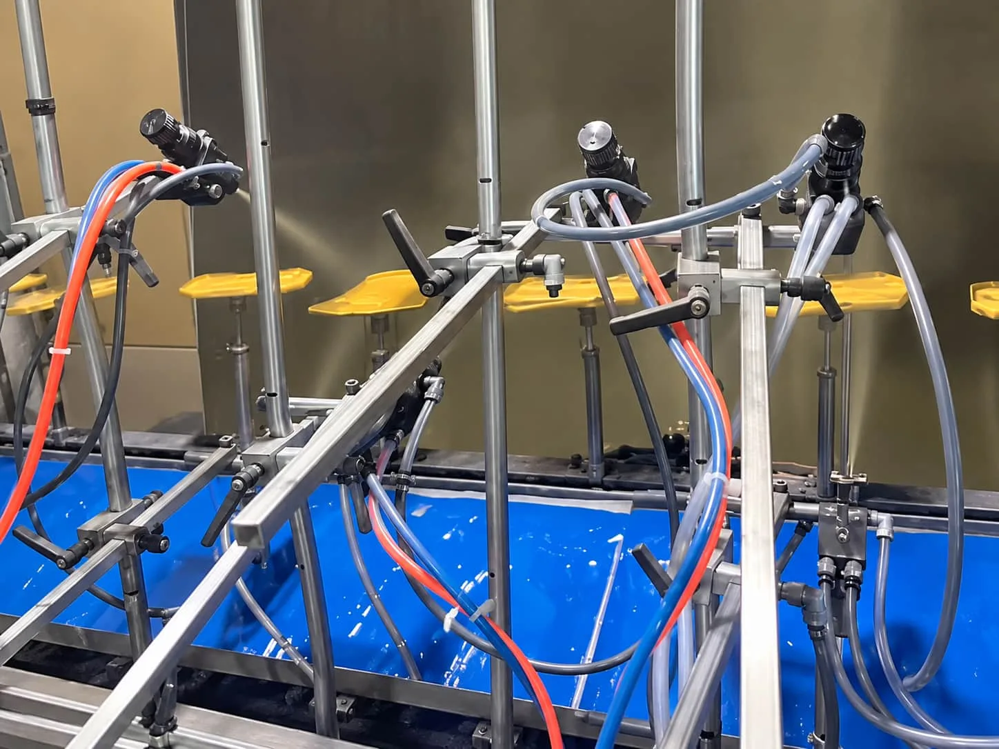 Spray coating equipment with nozzles and supply hoses for soft-touch surface treatment.